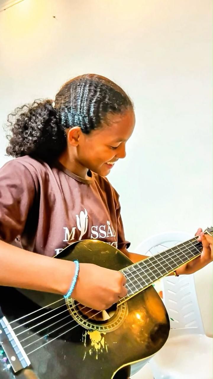 Menina tocando violão na aula de música